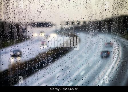 Vista attraverso una finestra immersa nella pioggia su un'autostrada Foto Stock