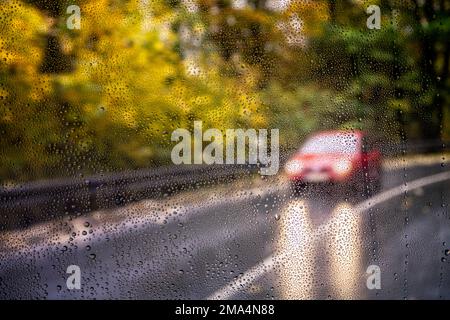 Vista attraverso un parabrezza bagnato dalla pioggia di un'auto in arrivo Foto Stock