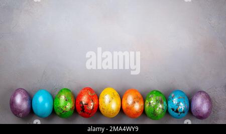 Concetto di Pasqua con uova di Pasqua colorate su sfondo grigio. Vista dall'alto con spazio di copia. Foto Stock