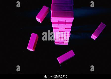 Il gioco per bambini in jenga di plastica rosa è iniziato come regalo di compleanno su uno specchio di legno. Foto Stock