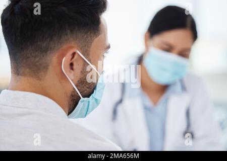 Ansioso per il vaccino. un uomo irriconoscibile che indossa una maschera facciale e che siede con il medico durante un consulto. Foto Stock