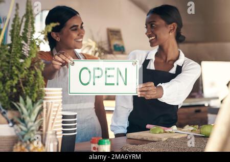 Im così fiero di fare questo con voi. due giovani donne d'affari che hanno un cartello aperto nel loro camion alimentare. Foto Stock