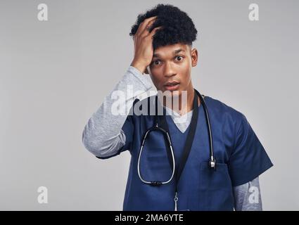 Im non pronto a condividere le notizie con il paziente. un'infermiera maschile che guarda stressata mentre si trova su uno sfondo grigio. Foto Stock