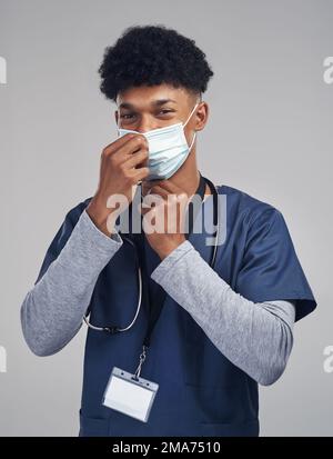 Im dare un contributo positivo alla mia comunità e società. un'infermiera che indossa una maschera chirurgica mentre si trova su uno sfondo grigio. Foto Stock
