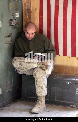 US Marine Corps (USMC) Sergente (SGT) Thomas Schaeffer, videografo da combattimento, 2nd Marine Division (MAR DIV), Combat Camera (COMCAM), si rilassa leggendo un libro all'interno dei confini del pulmino di produzione mobile COMCAM a Camp Blue Diamond ad Ar Ramadi, Iraq, durante l'operazione IRACHENA LIBERTÀ. Base: AR Ramadi Stato: Al Anbar Nazione: Iraq (IRQ) Foto Stock