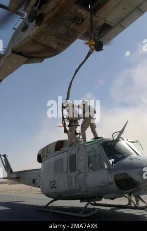 US Marine Corps (USMC) Marines di Combat Logistics Battaglione 2 (CLB-2) si ergono in cima a un USMC UH-1N Iroquois Huey, mentre lo agganciano a un USMC CH-53 Super Stallion, Marine Heavy Helicopter Squadron 466 (HMH-466), Naval Air Station (NAS) Miramar, California (CA), per un ascensore, da al Qaim, Iraq Durante l'operazione LA LIBERTÀ IRACHENA. Base: Al Qaim Stato: Al Anbar Paese: Iraq (IRQ) Foto Stock