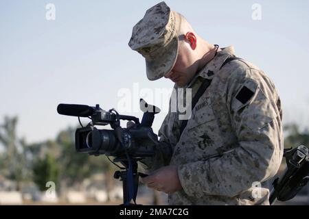 US Marine Corps (USMC) Sergeant (SGT) Thomas Schaeffer, videografo di combattimento, 2nd Marine Division (MAR DIV), Combat Camera (COMCAM), controlla l'angolo di visione della sua telecamera e la composizione delle melodie prima dell'inizio di una produzione video per il messaggio di Natale da Marine dal 2nd MAR DIV durante l'operazione IRACHENA LIBERTÀ. Base: AR Ramadi Stato: Al Anbar Nazione: Iraq (IRQ) Foto Stock