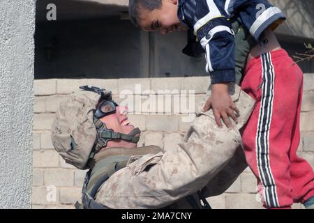 US Marine Corps (USMC) Private First Class (PFC) Erskine Blanton, Fox Company (F CO), 2nd Battaglione (BN), 2nd Marine Regiment (MAR REGT), gioca con un bambino iracheno mentre si ferma in sicurezza durante le operazioni a Kharma, Iraq, durante l'operazione LIBERTÀ IRACHENA. Base: Al Kharma Stato: Al Anbar Paese: Iraq (IRQ) Foto Stock