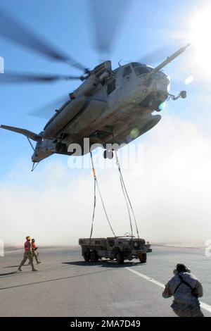 US Marine Corps (USMC) supporto all'atterraggio Marines tornare indietro dopo aver agganciato un camion rotto M-939A2 da 5 tonnellate a un elicottero USMC CH-53 Super Stallion da Marine Heavy Lift Squadron 466 (HMH-466), Naval Air Station (NAS) Miramar, California (CA), presso la base aerea di al Asad (AB), Iraq, durante l'operazione IRACHENA LIBERTÀ. Il carrello viene spostato in un'altra area della base per l'addestramento al sollevamento potenziato. Base: Al Asad Stato: Al Anbar Nazione: Iraq (IRQ) Foto Stock