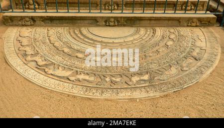 Sandakada Pahana, conosciuta anche come Moonstone, è una caratteristica unica dell'architettura singalese dell'antico Sri Lanka. È una lastra di pietra semicircolare intagliata, di solito posta sul fondo delle scale e degli ingressi. Visto per la prima volta nell'ultima fase del periodo Anuradhapura, il sandakada pahana si è evoluto attraverso i periodi Polonnaruwa, Gampola e Kandy. Secondo gli storici, la sandakada pahana simboleggia il ciclo di Sansāra nel buddismo. L'antica cronaca Mahavamsa e la letteratura Pali come la Samantapasadika fanno riferimento alla sandakada pahana come patika. Sri Lanka. La prima sandakada pa Foto Stock