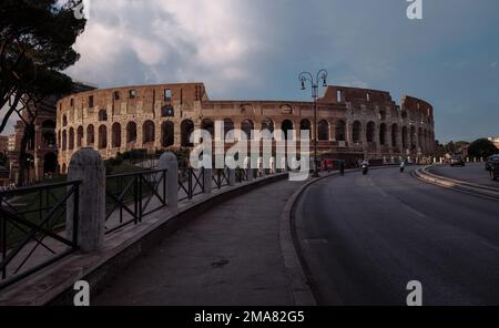 Il Colosseo a Roma visto dalla strada che crea una linea curva di testa verso l'anfiteatro. Foto Stock