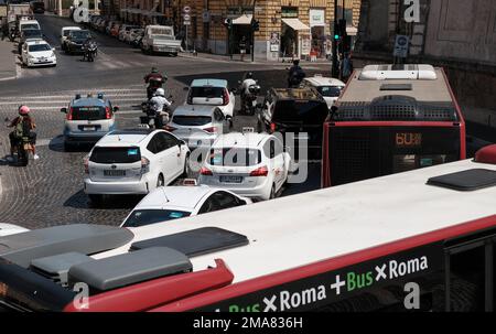 Un trafficato bivio stradale a Roma Italia con autobus, auto e motociclette in attesa di andare al cambio del semaforo. Foto Stock