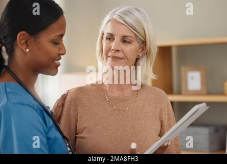 Non deve mai preoccuparsi di non essere lì. un medico che utilizza un tablet digitale durante una consultazione con una donna anziana a casa. Foto Stock