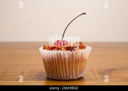 Goiânia, Goias, Brasile – 18 gennaio 2023: Dettaglio di un bombarocado, tipico dolce brasiliano, cotto all'interno di una casseriera di carta, con una ciliegia in cima. Foto Stock