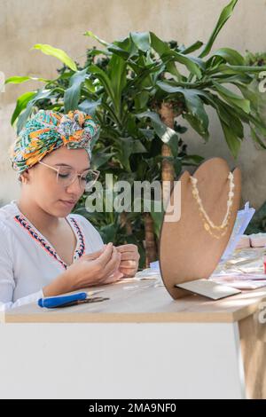 Donna artigiana fare collane nel suo laboratorio di casa. Foto Stock