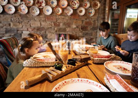 Quattro bambini si siedono in autentico ristorante ucraino, guardando sui telefoni. Foto Stock
