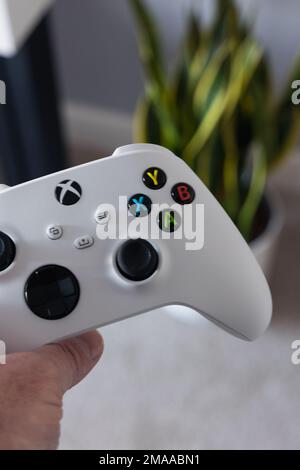 LONDRA - 16 GENNAIO 2023: Uomo che gioca a Xbox Series S controller bianco nel soggiorno moderno Foto Stock