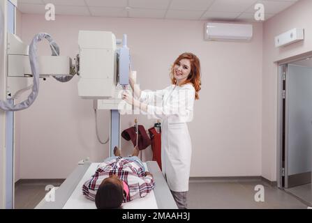 Una giovane radiologa femminile, mentre conduce una radiografia medica di una giovane donna afro-americana in un laboratorio Foto Stock