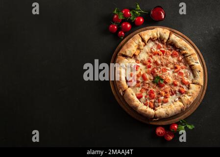 Pizza napoletana con spezie, pomodori e mozzarella su fondo scuro. Pizza margarita con mozzarella, salsa di pomodoro, spinaci spessi Foto Stock