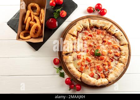 Set di pizza e spuntini su sfondo bianco. Margarita pizza e snack anelli di cipolla fritti in panatura Foto Stock