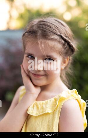 Ritratto della bambina che tiene la mano su un assegno e hanno ladybug rosso sull'altro in estate gzrden sera Foto Stock