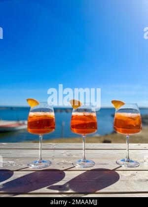 Uno shot verticale di tre cocktail di agrumi arancioni su una spiaggia soleggiata Foto Stock