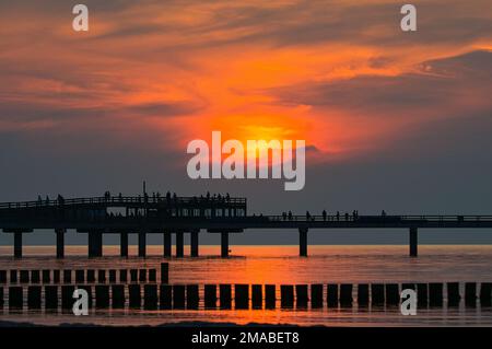Paesaggi mozzafiato di persone al nuovo molo Heiligenhafen sul Mar Baltico, ammirando il colorato tramonto sul mare Foto Stock