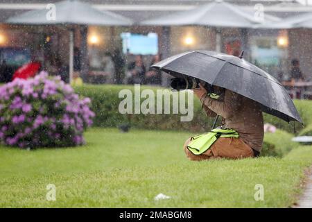 20.05.2022, Germania, bassa Sassonia, Hannover - fotografo stampa che scatta foto sotto un ombrello in condizioni di maltempo. 00S220520D082CAROEX.JPG [MODELLO RELE Foto Stock