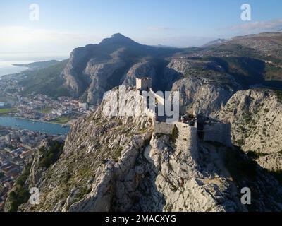 Vista aerea del drone della città di Omis in Croazia. La posizione è il punto di incontro tra il fiume Cetina e il mare Adriatico. Bellissima città vicino alle montagne. Foto Stock