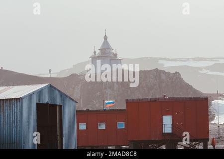 Alcuni edifici della Stazione Russa di Bellingshausen e la Chiesa della Trinità sulla montagna in una giornata di nebbia Foto Stock