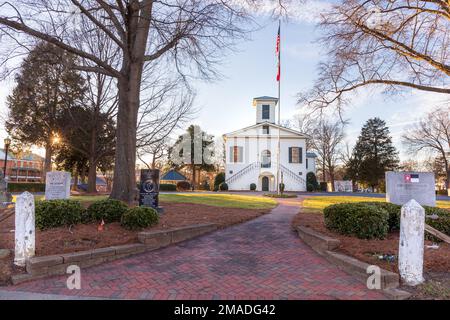 DALLAS, NC, USA-5 GENNAIO 2023: Ingresso principale allo storico edificio e ai terreni della Gaston County Court House del 1848. Passaggio pedonale in mattoni, palo della bandiera, monumento Foto Stock