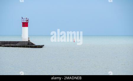 Faro e cormorano di Port Stanley: Un grande cormerante nero in cima al faro alla fine del molo di Port Stanley contro le calme acque blu del lago Erie. Foto Stock