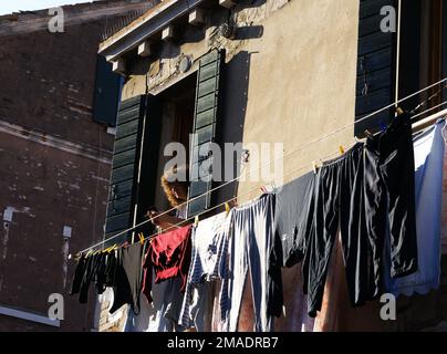 Un residente locale guarda fuori dalla finestra sulla strada di Venezia, Italia, 15 novembre 2008 Foto Stock