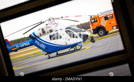 Langenhagen, Germania. 16th Jan, 2023. Un elicottero di polizia MD 902 esploratore della polizia elicottero squadrone della bassa Sassonia è parcheggiato sul terreno dell'aeroporto di Hannover-Langenhagen - un veicolo di emergenza del vigili del fuoco dell'aeroporto guida oltre l'elicottero. Credit: Moritz Frankenberg/dpa/Alamy Live News Foto Stock