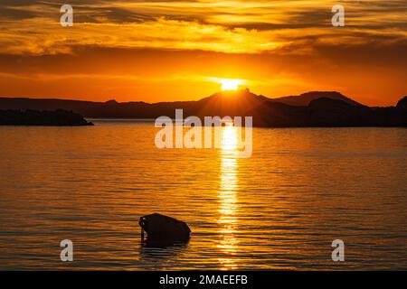 Vista sul tramonto d'oro colorato: La costa della Sardegna settentrionale e le lontane isole di Caprera e la Maddalena con il cielo rosso brillante e la domenica. Foto Stock