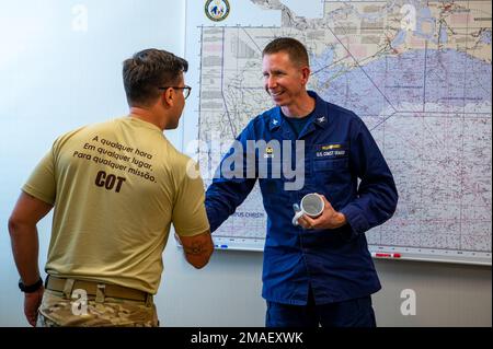 Jason Smith, comandante del settore della Guardia Costiera Houston-Galveston, dà una tazza di settore e una moneta di sfida ad un agente del Comando de Operações Táticas (COT), un'unità tattica d'élite della polizia federale del Brasile, durante la loro visita a varie unità della Guardia Costiera in tutto il Texas, 26 maggio 2022. LA COT ha visitato le unità e il personale della Guardia Costiera in Texas per saperne di più sulle missioni, i beni e l'addestramento della Guardia Costiera. Foto Stock