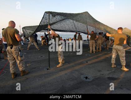 060723-N-6403R-013. [Complete] Scene Caption: US Marine Corps (USMC) Marines assegnato alla 24th Marine Expeditionary Unit (MEU) (Special Operations Capable (SOC)) ha istituito una rete di camoflage sul ponte di volo della US Navy (USN) Austin Class Anfibious Transport Ship Dock USS TRENTON (LPD 14). I marinai della USN della Wasp Class, nave d'assalto anfibio USS IWO JIMA (LHD 7) e della USMC Marines della 24th MEU (SOC) stanno assistendo i cittadini americani a bordo DELLA TRENTON. Il TRENTON sta per essere implementato regolarmente e sta assistendo il comando centrale degli Stati Uniti (US CENTCOM) e la Marine Expeditionary Unit 24th Foto Stock