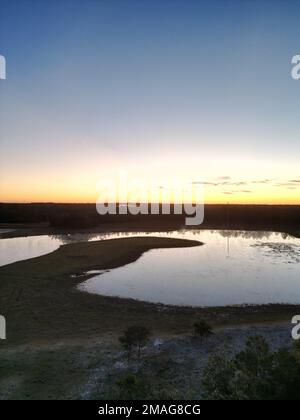 Una vista aerea di un lago in una zona rurale al tramonto Foto Stock