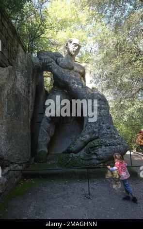 Un bambino vicino ad un'enorme statua raffigurante Ercole che combatteva Caco, chiamata anche Bosco Sacro nel Parco dei Mostri di Bomarzo. Viterbo, Italia Foto Stock