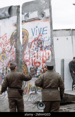 In piedi sul lato occidentale della Germania, i poliziotti della Germania orientale osservano la recente apertura nel muro di Berlino a Potsdamer Platz. Base: Berlin Nazione: Germania / Germania (DEU) Foto Stock
