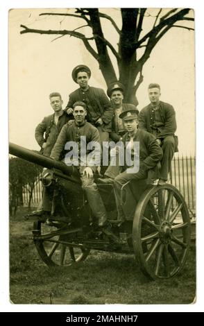 Cartolina originale del WW1 di un gruppo di giovani uomini del reggimento reale di Norfolk che si scompigliano in cima ad un campo di allenamento con una pistola da campo. Una rara fotografia di giovani che stanno per essere inviati in prima linea, eccitati a lasciare casa, prima che conoscano gli orrori delle trincee. Foraggio di cannone. Circa 1916 Regno Unito Foto Stock