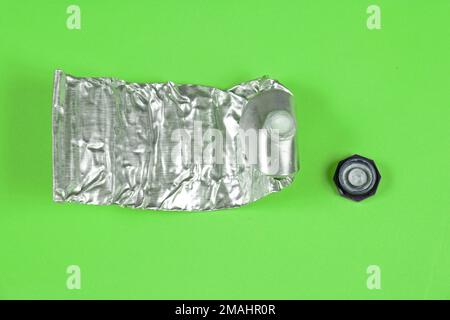 Tubo in argento metallico riccio usato con coperchio in plastica isolato su sfondo verde Foto Stock