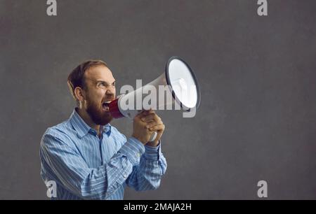 L'uomo bearded in una camicia blu gridò forte in un megafone. Foto Stock