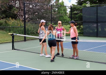 Quattro giocatori femminili di pickleball toccano le pagaie dopo una partita competitiva. Foto Stock