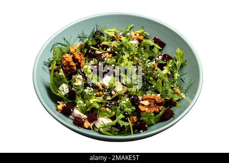 Insalata con barbabietole, rucola, prezzemolo, erbe aromatiche feta, noci in una terrina su fondo isolato. Foto Stock