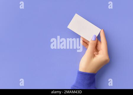 Womans mano che tiene il biglietto da visita su sfondo viola. Modello di lavoro aziendale Foto Stock