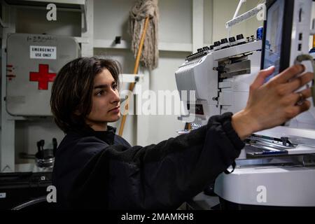 MARE DELLE FILIPPINE (30 maggio 2022) Airman Elisa Vega, di Apopka, Fla., ricama un nametag a bordo della portaerei di classe Nimitz USS Abraham Lincoln (CVN 72). Abraham Lincoln Strike Group è in fase di implementazione pianificata nell'area delle operazioni della flotta 7th degli Stati Uniti per migliorare l'interoperabilità attraverso alleanze e partnership e al tempo stesso fungere da forza di risposta pronta a sostegno di una regione indomPacifico libera e aperta. Foto Stock