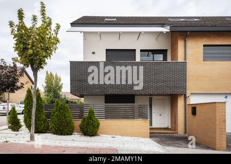 Facciate di strada di un'urbanizzazione con case semi-indipendenti singola-famiglia con alberi e siepi decorativi Foto Stock