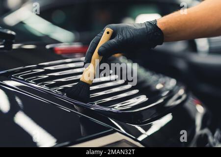 Uomo con guanti di protezione pulizia cruscotto auto con panno in