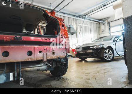 Vettura danneggiata con ammaccature e graffi in un'officina di riparazione carrozzeria pronta per le riparazioni. Foto di alta qualità Foto Stock